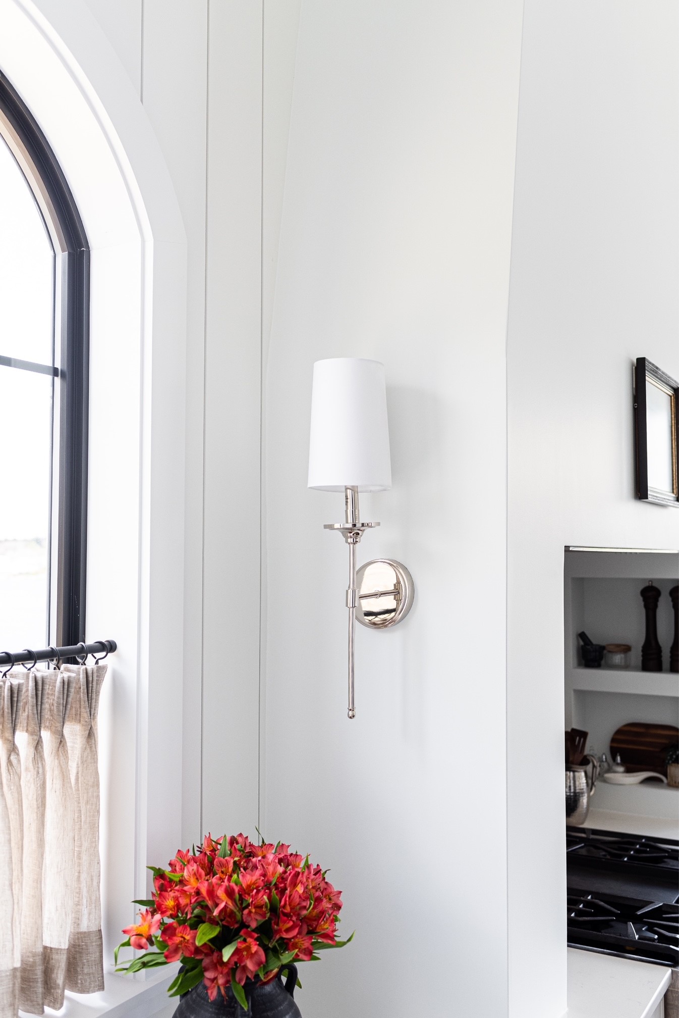 Z-Lite's Emily Wall Sconce with nickel finish hangs beside the encased range hood